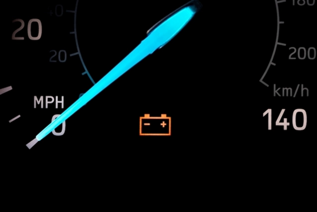 Black speedometer with its needle pointing to 0 and the battery icon lit up