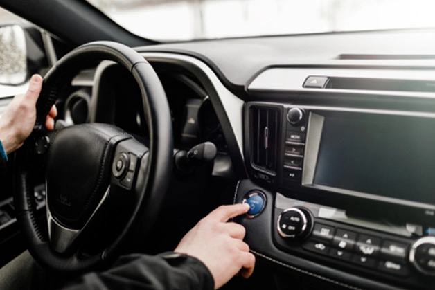 person in a car pressing the start and stop button