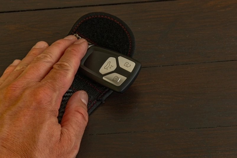 A hand holding a pair of car keys on a table