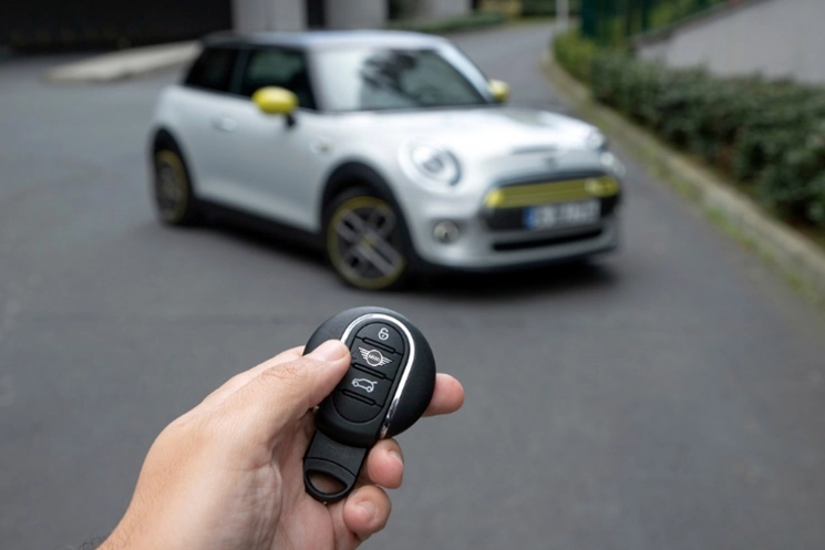hand holding a MINI key in front a MINI car 