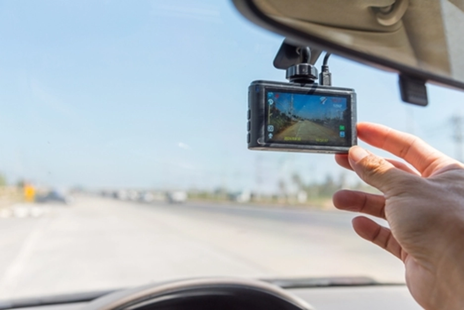 a hand touching a dashcam mounted in a car