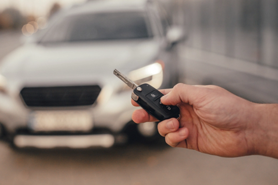 a hand holding a key in front of a car