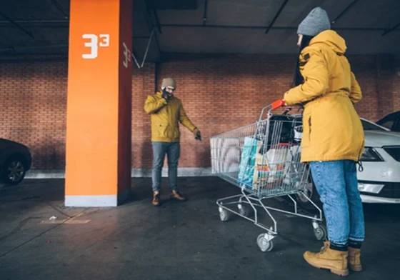 A couple with a shopping trolley standing in front of an empty parking space