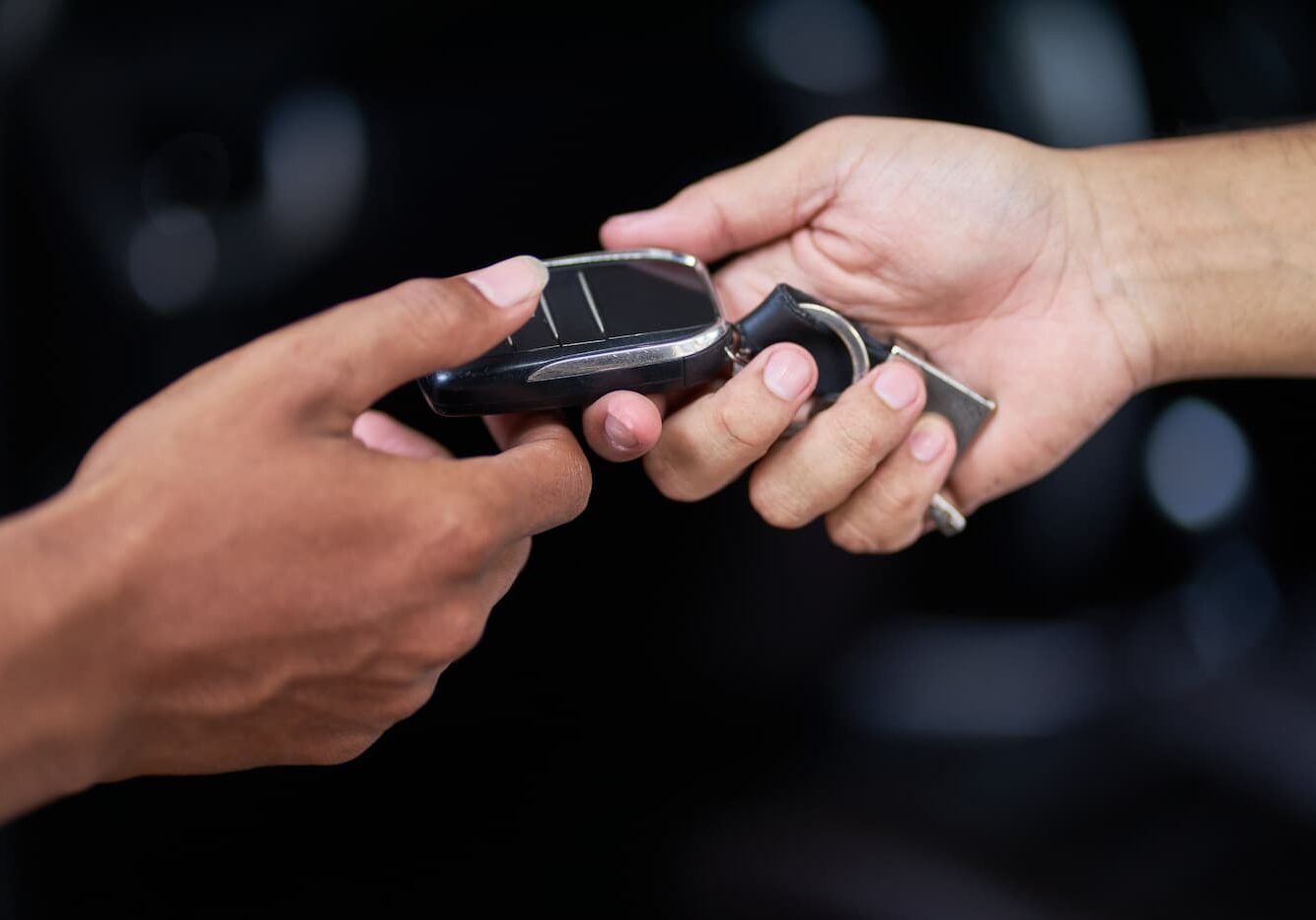 A car key being passed between two hands.